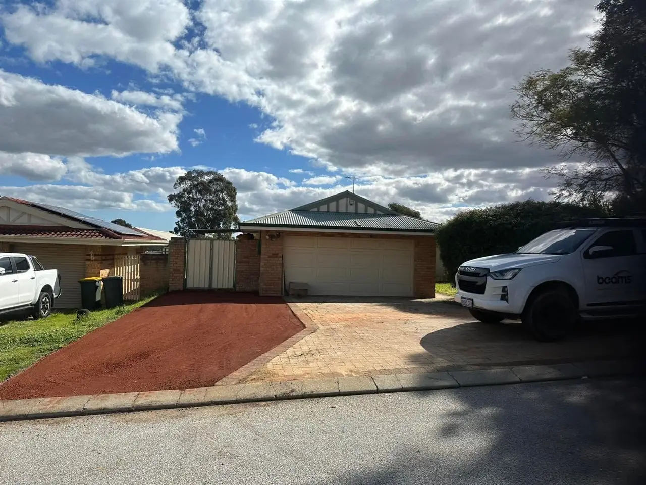 Finished red road gravel hardstand beside a brick home's driveway