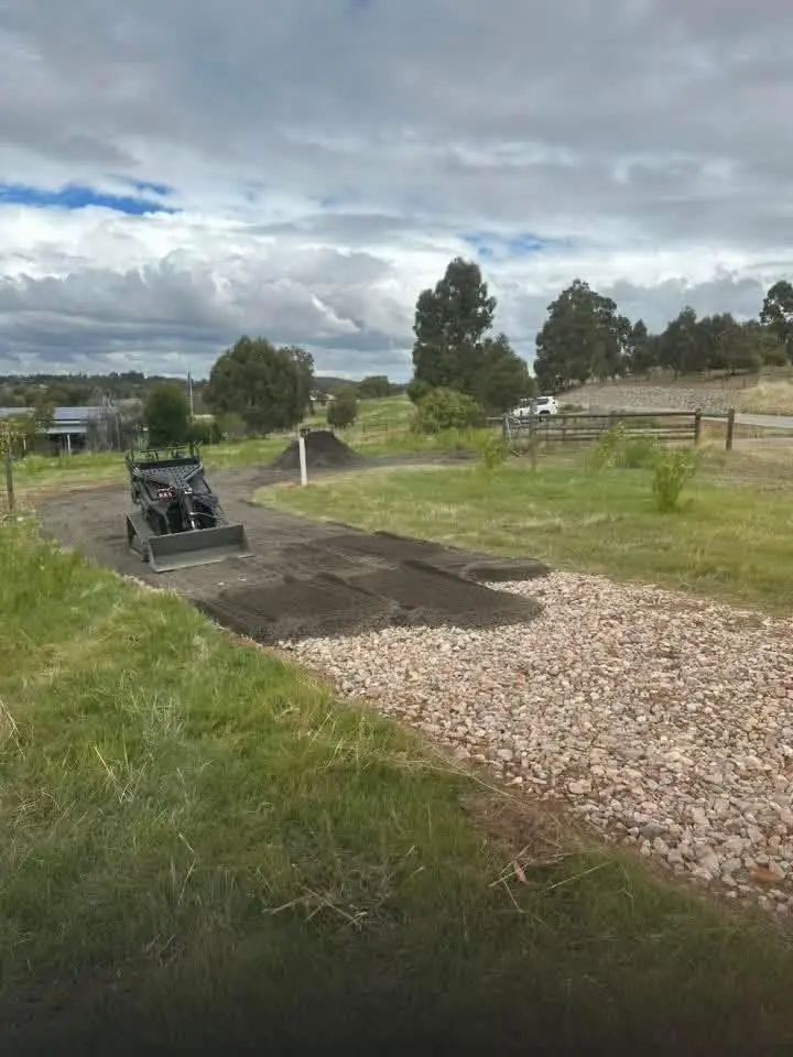 Tracked mini loader with a bucket on a gravel driveway