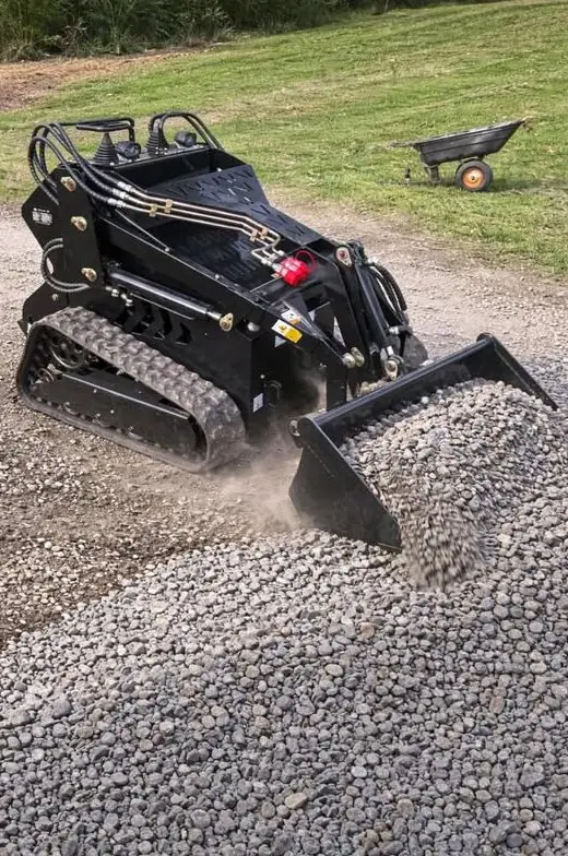 Mini loader pushing a bucket of gravel