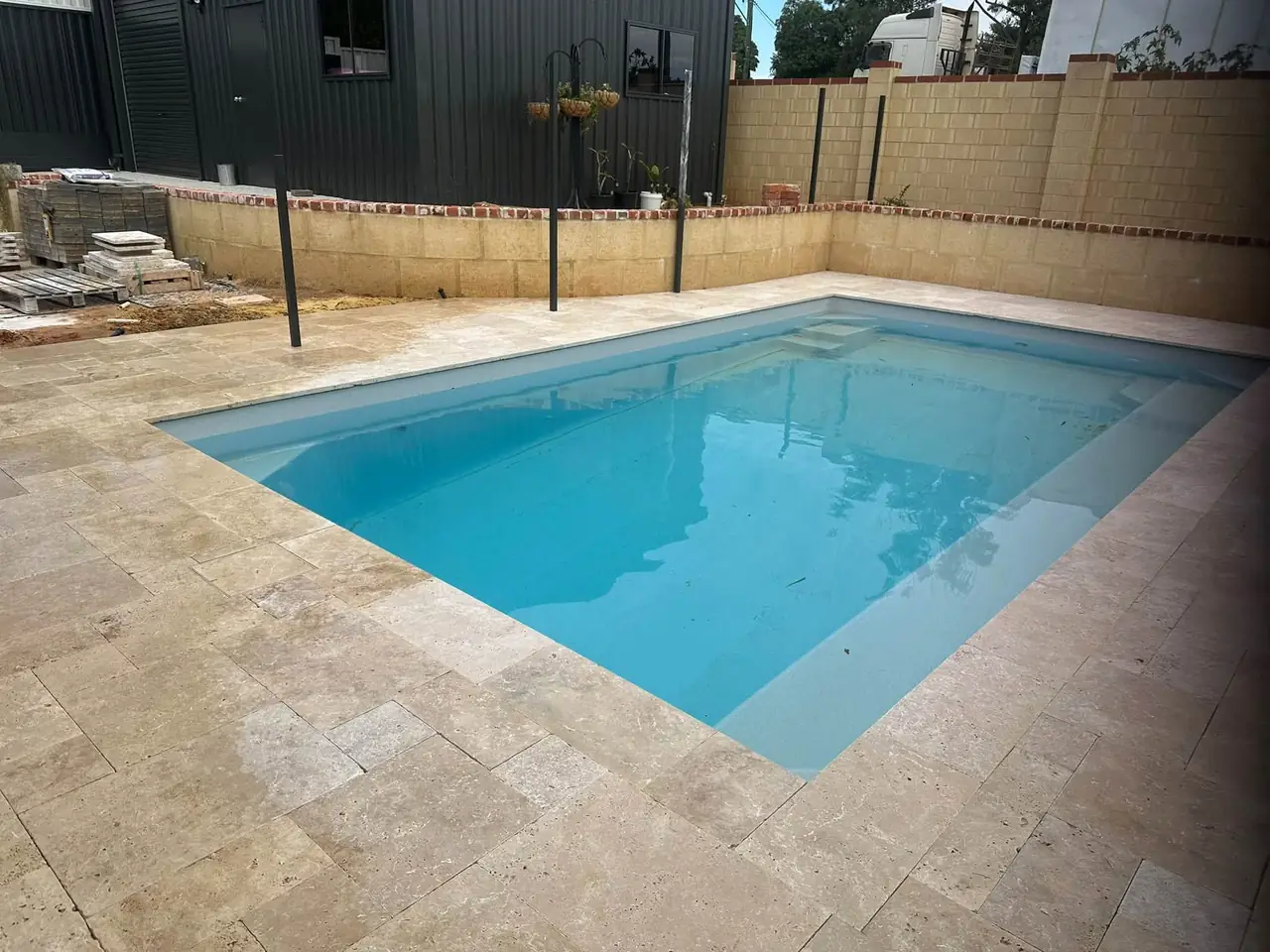 Finished travertine paving around a backyard pool