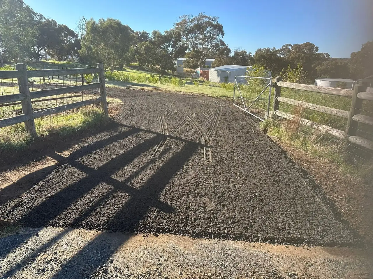 Recycled asphalt driveway laid and compacted along a rural fence line